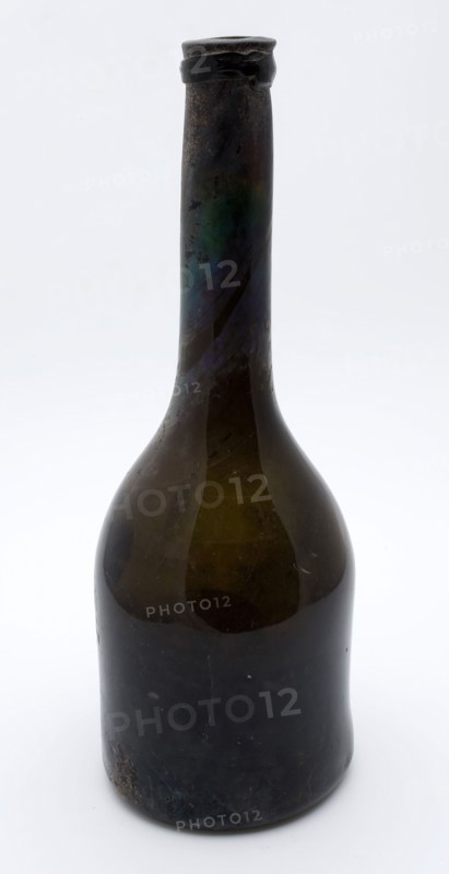 Brown, transparent, cylindrical bottle with long neck, bottle holder soil found glass, hand-blown glass application Cylindrical