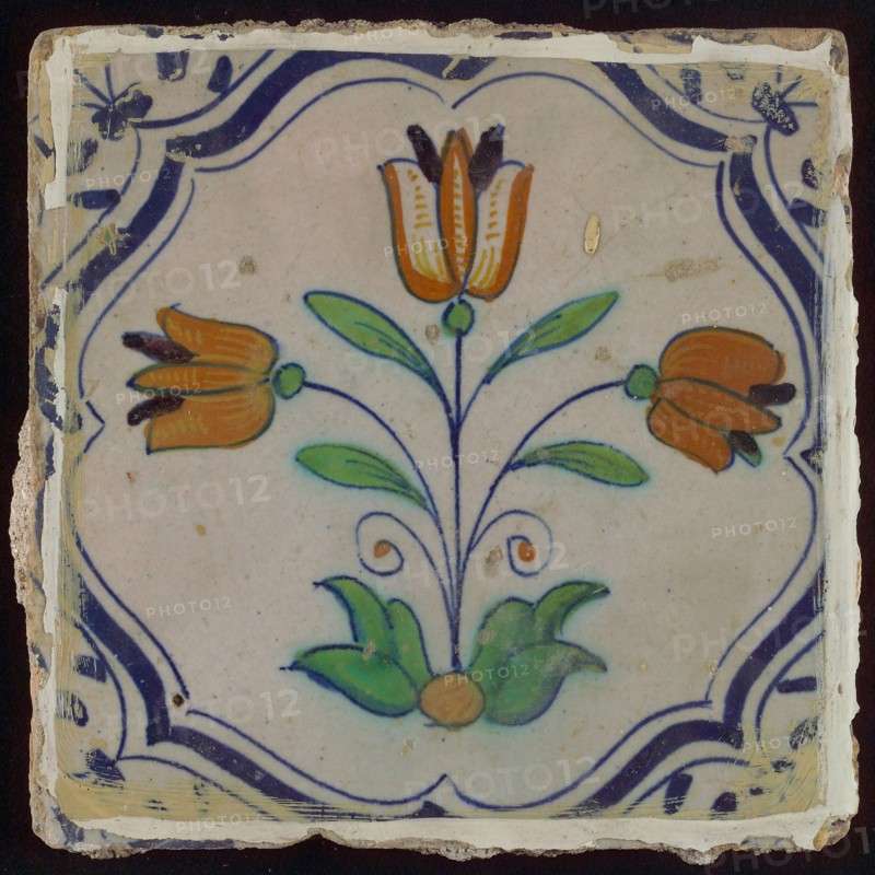 Tile, three-tier in blue, green, orange and purple on white, inside frame with accolades, corner motif, wing, wall tile