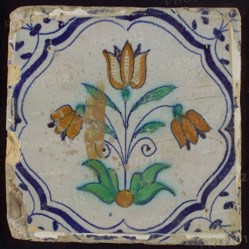 Tile, three-tier in blue, green, orange and purple on white, inside frame with accolades, corner motif, wing, wall tile