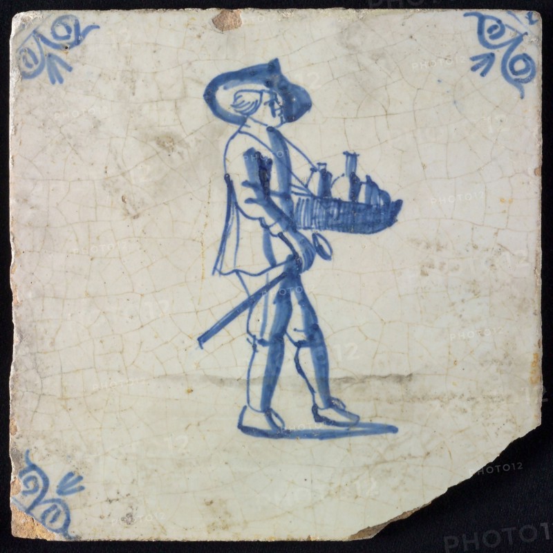 Occupation tile, blue with man with hat and leaf with bottles and walking stick in his hand, corner motif, ox-head, wall tile
