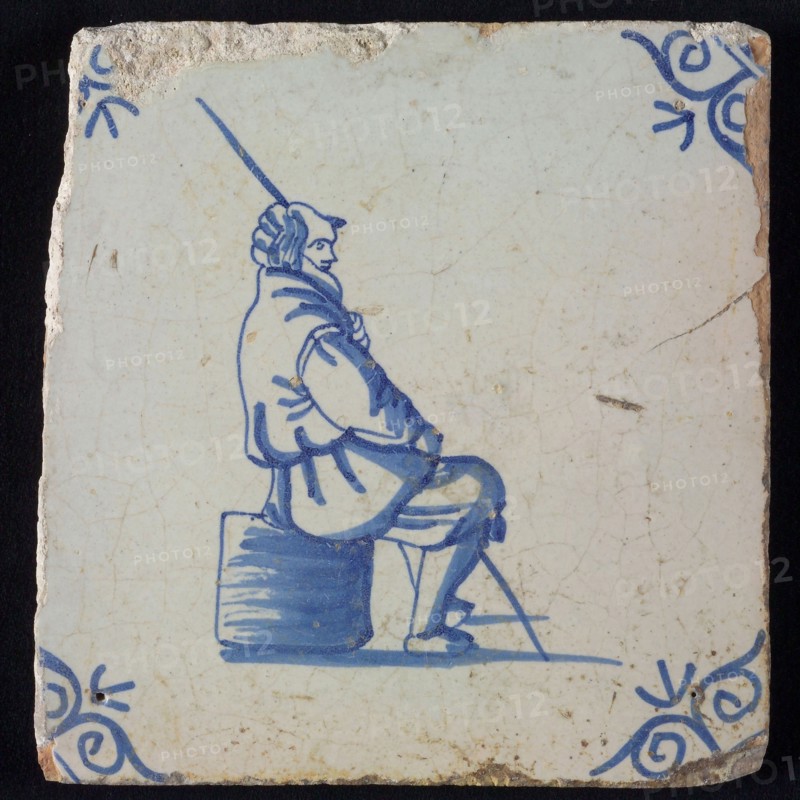Occupation tile, blue with man sitting on block or shepherd with staff, corner pattern ox-head, wall tile tile sculpture ceramic