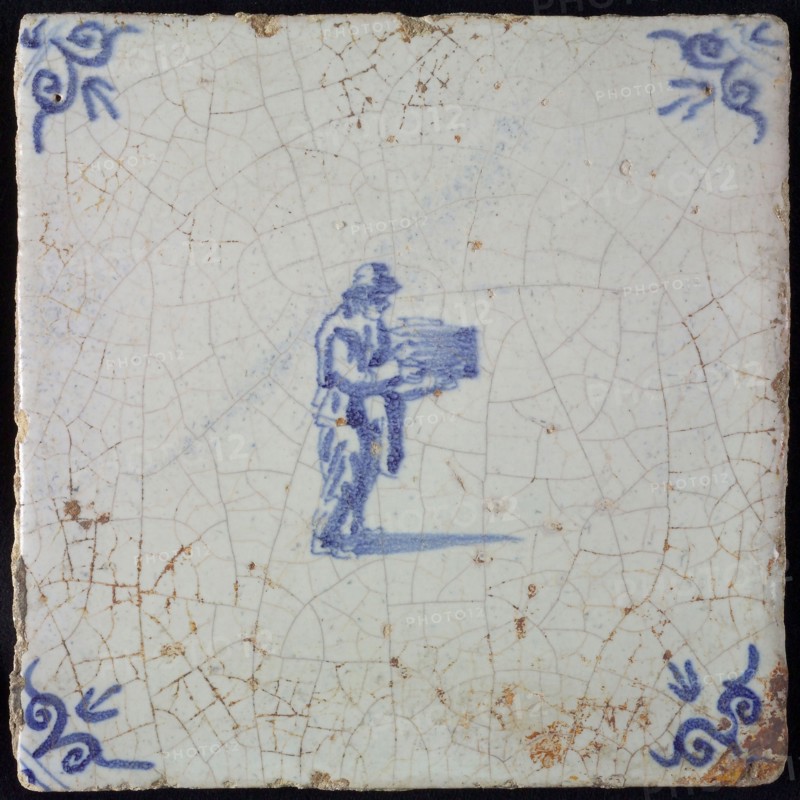 Occupation tile, blue with standing man with pile in his hands, corner motif ox's head, wall tile tile sculpture ceramic