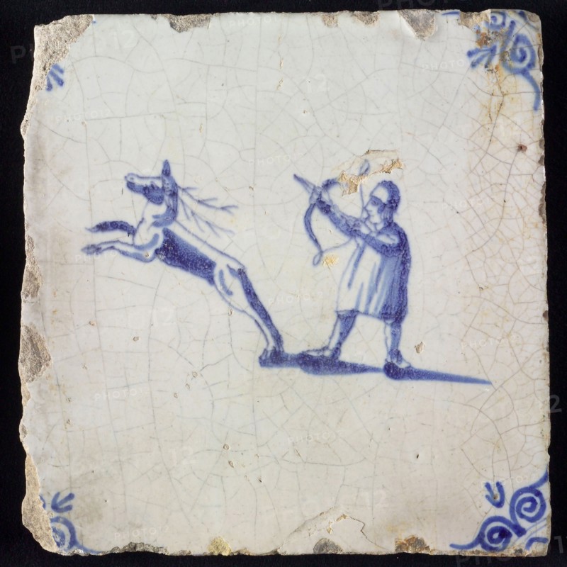 Figure tile, blue with hunter with bow and arrow, shooting on jumping deer, corner pattern ox-head, wall tile tile sculpture