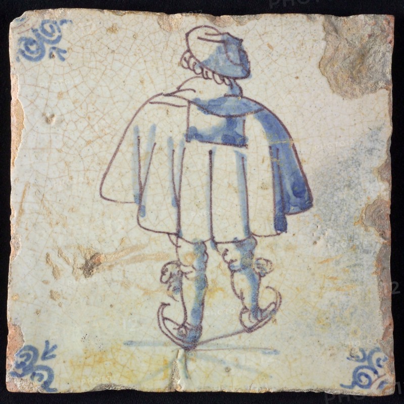 Figure tile, blue with skating man, with wide cape, seen on the back, corner pattern ox head, wall tile tile sculpture ceramic