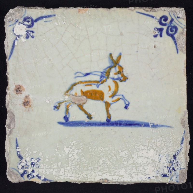 Animal tile, trotting horse or donkey to the right with loose halter, in blue and brown on white, corner motif oxen head, wall