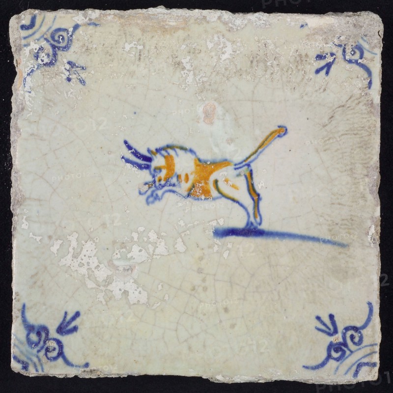 Animal tile, attacking bull to the left, blue and brown on white, corner motif ox's head, wrinkled glaze, wall tile