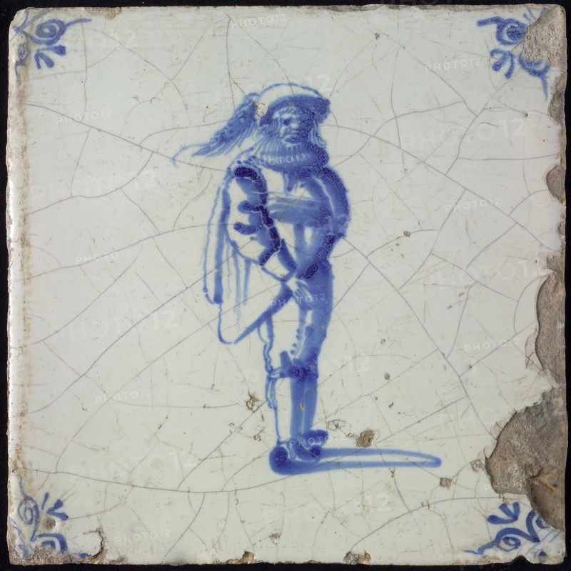 Figure tile, blue with standing man with limp beret with plume, corner motif ox's head, wall tile tile sculpture ceramic