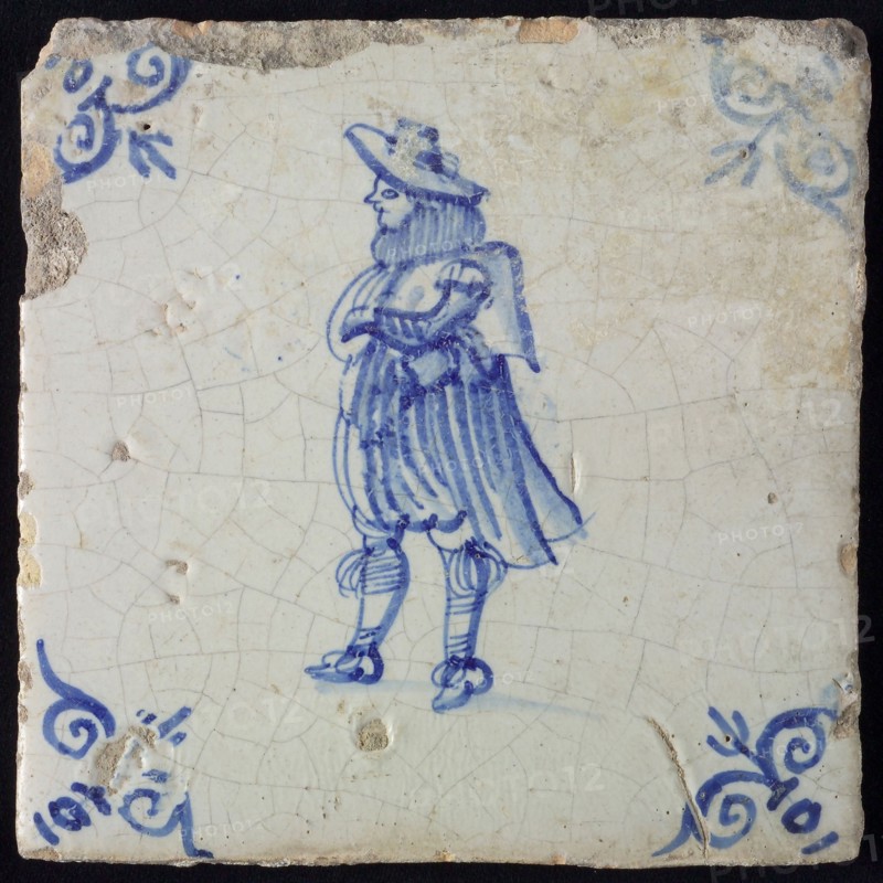 Figure tile, blue with nobleman with wide cape, breeches and big hat, corner pattern ox's head, wall tile tile sculpture ceramic