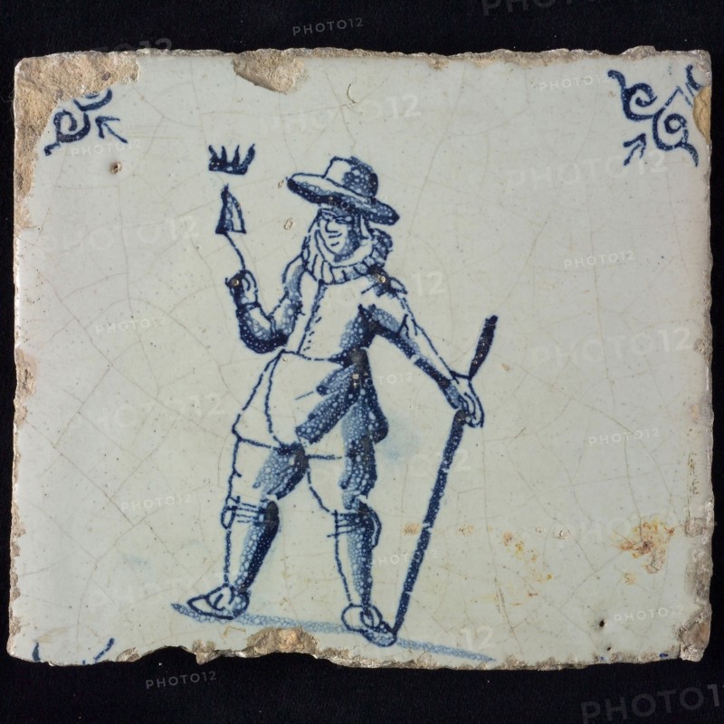 Occupation tile, blue with bricklayer with crowned trowel, big hat and lace collar, corner pattern ox head, wall tile