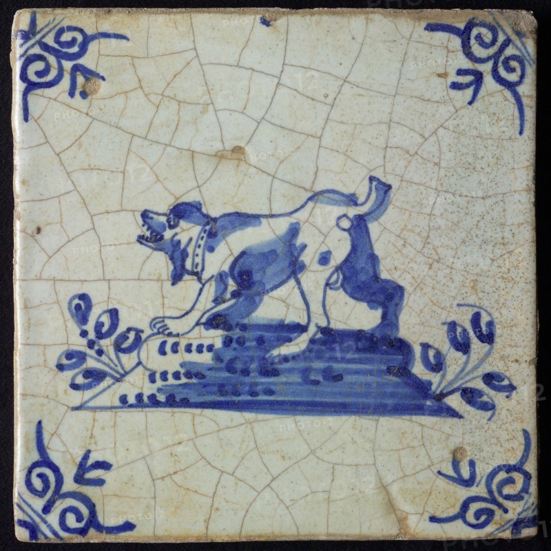 Animal tile, barking standing dog to the left on plot, in blue on white, corner motif oxen head, wall tile tile sculpture
