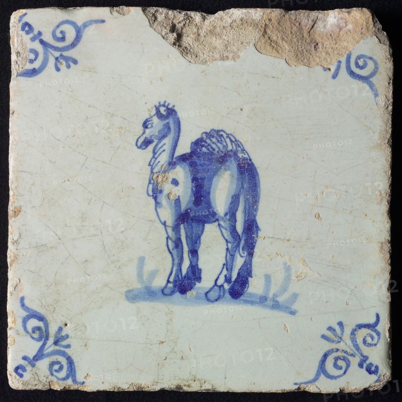 Animal tile, standing dromedary to the left on ground, in blue on white, corner pattern ox head, wall tile tile sculpture