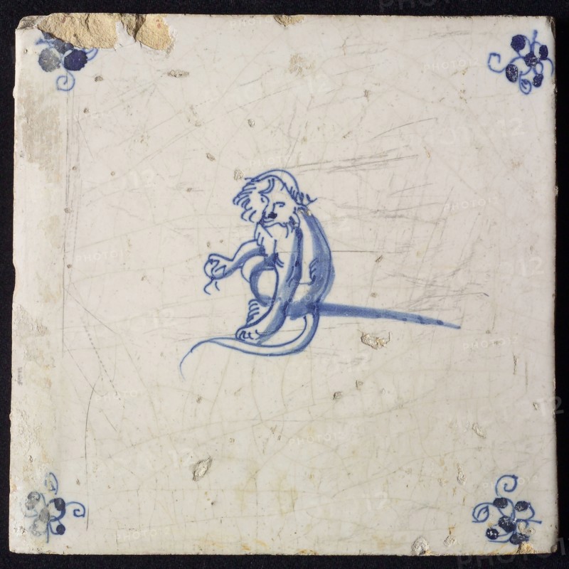 Animal tile, sitting monkey to the right with an unknown object in one leg, in blue on white, corner motif spider, wall tile