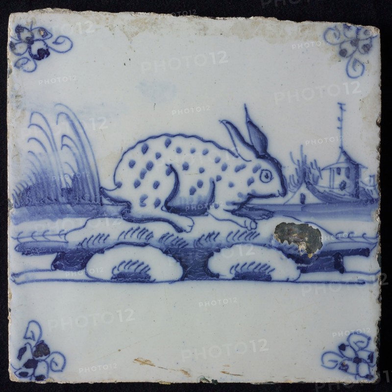 Animal tile, sitting dotted hare to the right on continuous plot, building with tower in the background, in blue on white