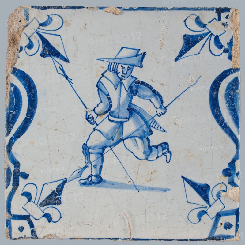 Figure tile, blue with man running with two spears, between balusters with lily, wall tile tile sculpture ceramic earthenware