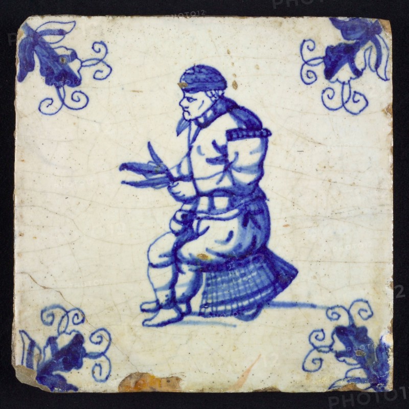 Figure tile, blue with man sitting on basket, cleans fish with knife, Corner motif, wall tile tile sculpture ceramic earthenware