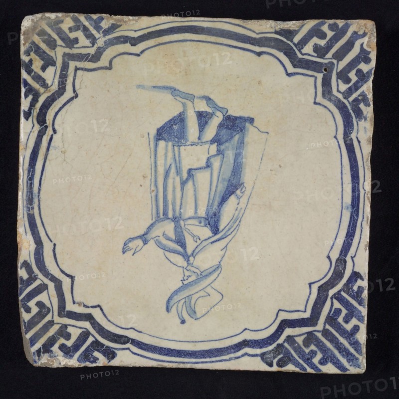 Figure tile, blue with nobleman with big hat and long coat, in scalloped frame with braces, corner motif meander, wall tile