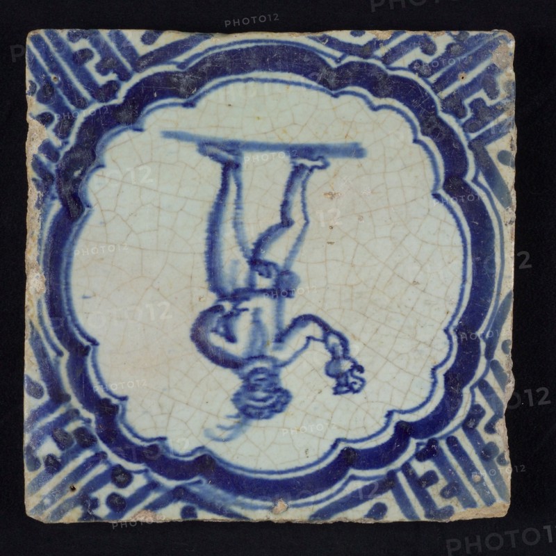 Figure tile, blue with standing man with beret and plume, with bird and jug in the hand, scalloped frame with braces, corner