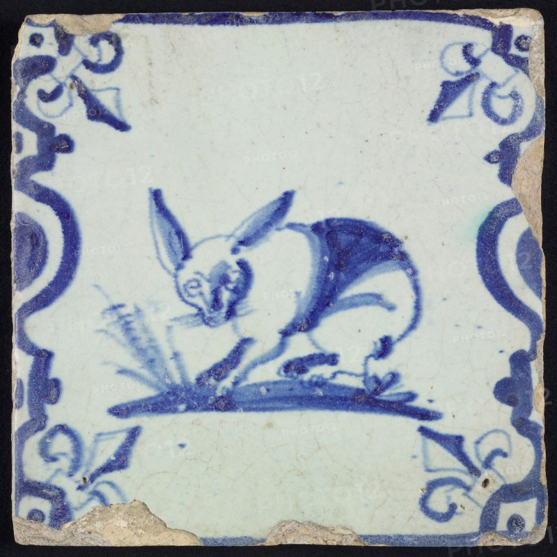 Animal tile, standing hare to the left on ground between balusters, in blue on white, corner pattern French lily, wall tile