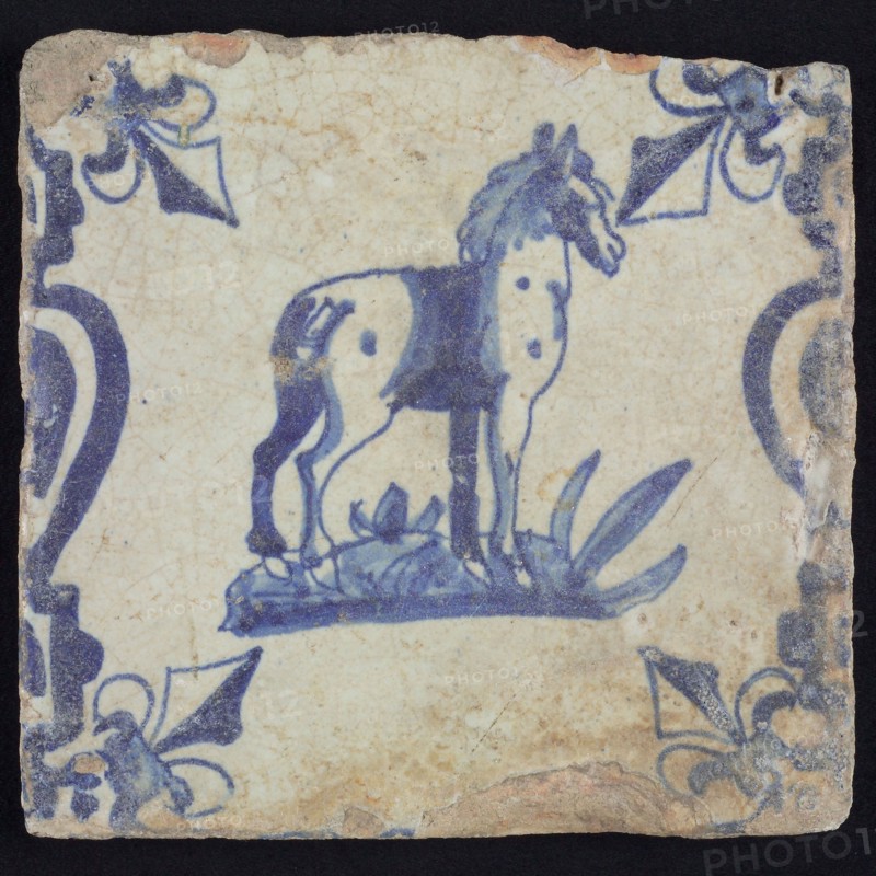 Animal tile, standing horse to the right on ground between balusters, in blue on white, corner pattern french lily, wall tile