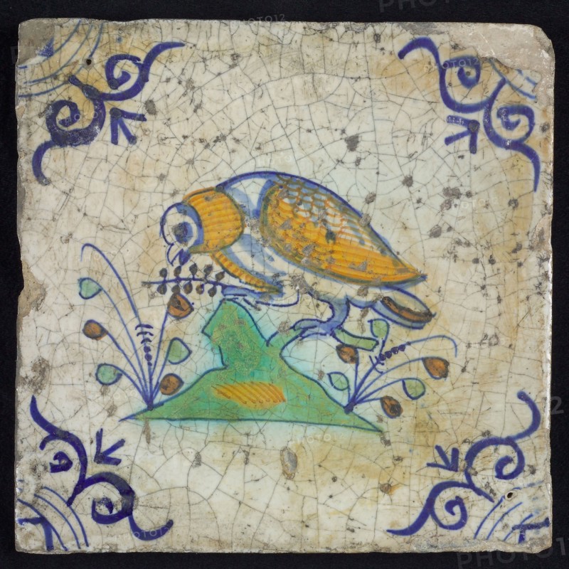 Animal tile, bird with berry twig, on branch to the left in orange, yellow, green and blue on white, corner pattern ox head