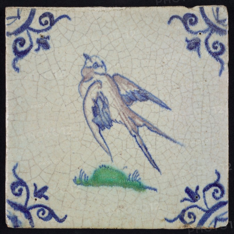 Animal tile, flying bird to the left in purple, green and blue on white, corner motif ox's head, wall tile tile sculpture