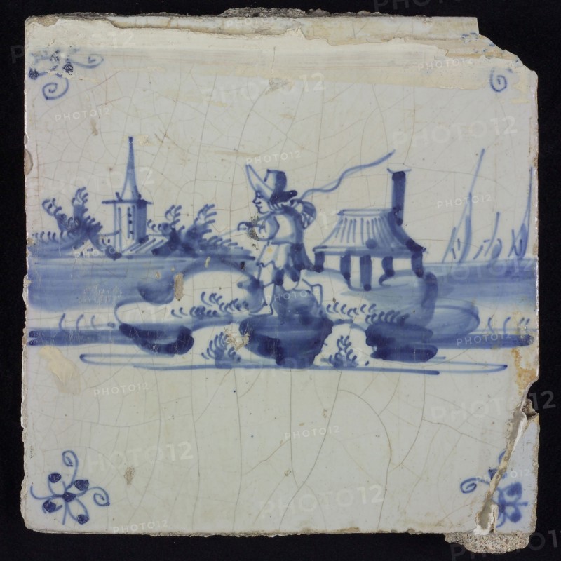 Scene tile, blue with landscape with fisherman with rod and knapsack, in the background church, house and ships, corner motif