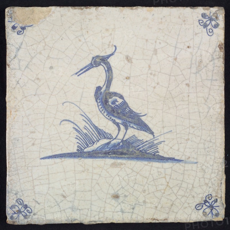 Animal tile, standing heron to the left on ground, in blue on white, corner motif spider, wall tile tile sculpture ceramic