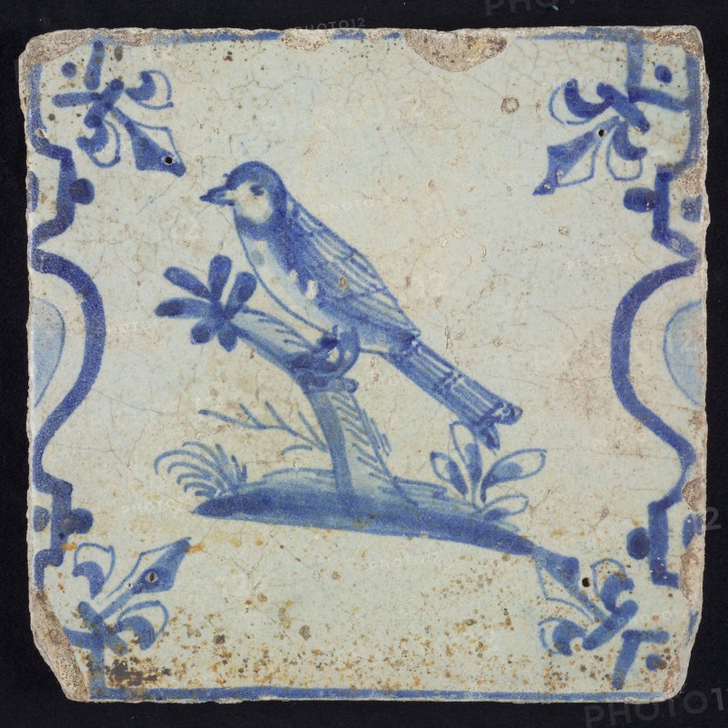 Animal tile, bird on branch on plot to the left between balusters in blue on white, corner pattern French lily, wall tile