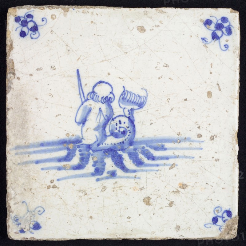 Sea creature tile, in blue on white, on the back seen naked man with fish tail in water to the right, in hand sword, corner