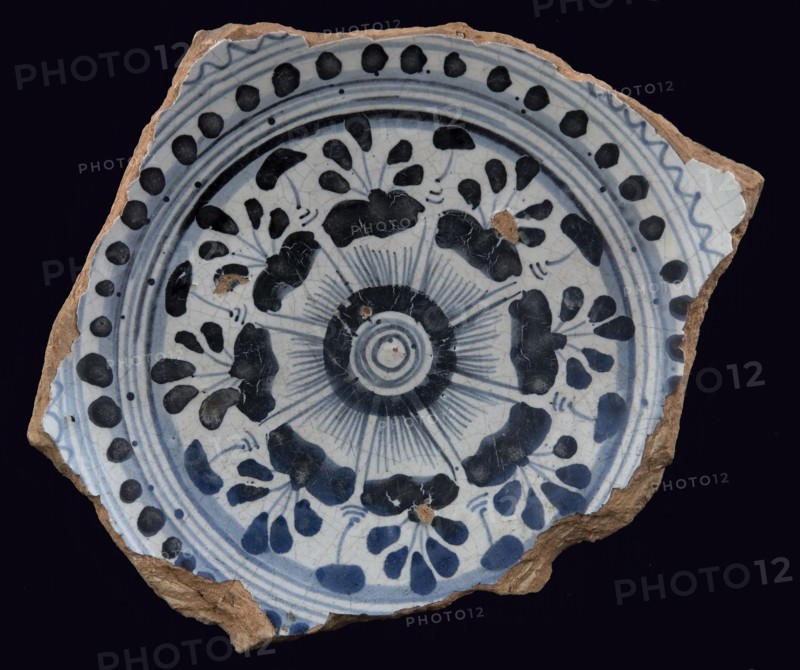 Fragment majolica plate, blue on white, stylized floral pattern on mirror, dot and serrated edge surrounded by concentric