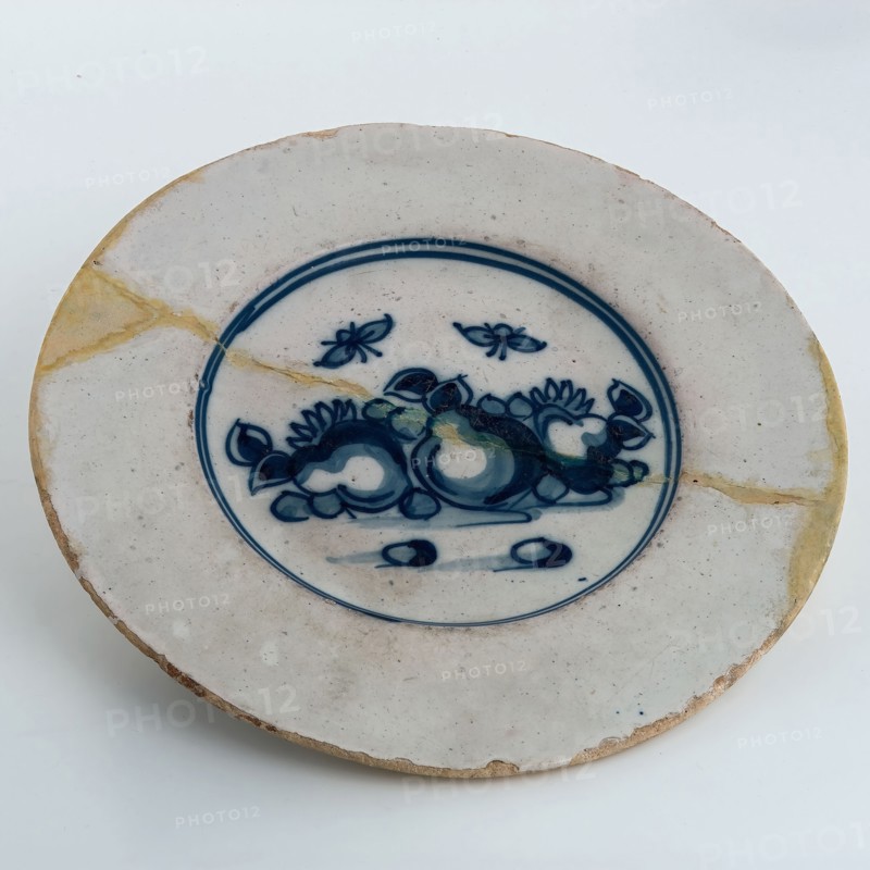Faience plate on stand, blue decor on white background, fruit and insects, plate crockery holder soil find ceramic pottery glaze
