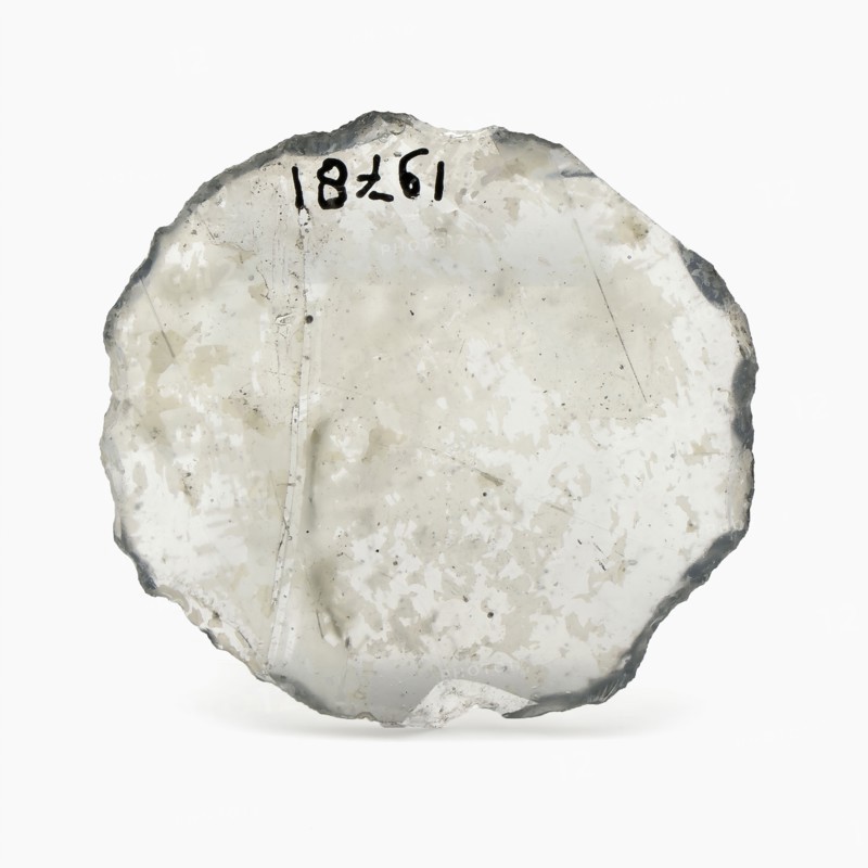 Oval glass disk of thin window glass, disc artifact soil find glass, cast cut cut Oval slice thin window glass