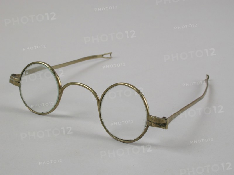 Glasses with round lenses on strength, frame of brass with wide bridge and hinged springs that end in loop shape, spectacle eye