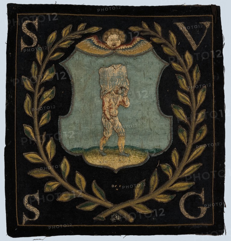 Blazon of black cloth with application and (gold) embroidery, cherub head above shield with pocket carrier to the right, laurel