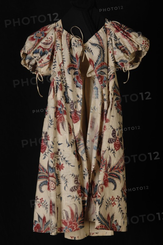 Empire children's dress or jacket of cotton chintz, white fond with large multicolored flowers, red, blue and purple, puff
