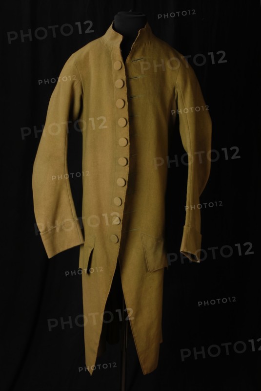 Light green sheet skirts with upright narrow collar, button closure of ten buttons, scalloped pocket flaps, pawncoat skirt