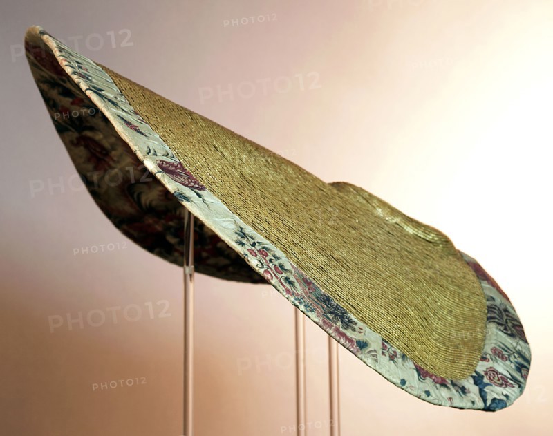 Large semi-circular sun hat, natural colored ribbon straw, low flat ball, very wide rim, lining of chintz and edge of pleated