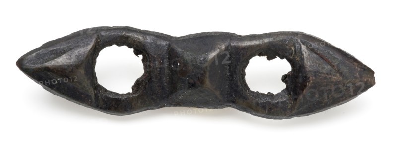 Elongated bronze fittings with two round openings, clothing accessory clothes batter ground find bronze copper metal, cast