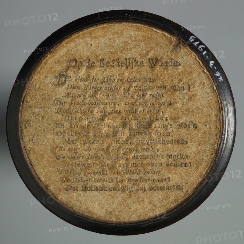 One-sided wooden medallion, covered with paper, with printed text OP DE BEESTELIJKE WOEDE, penny box holder wood paper, text