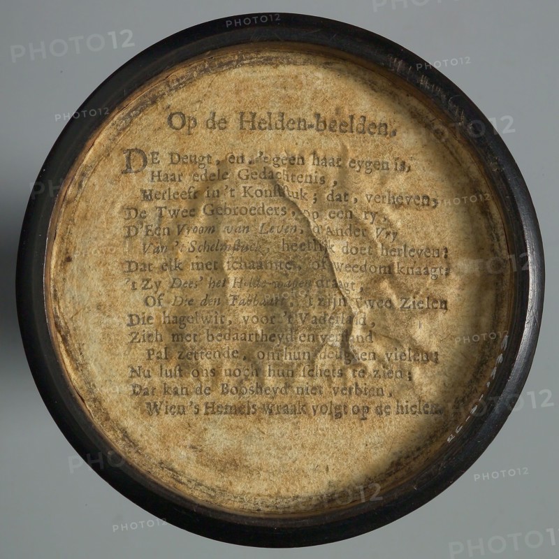 One-sided wooden medallion, covered with paper, with printed text OP DE HELDEN-BEELDEN, penny box holder of wood paper, Text