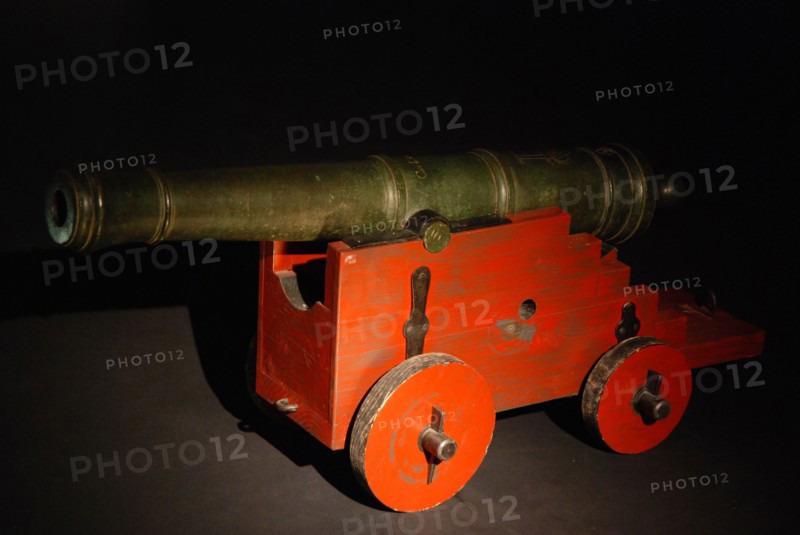 C. en I. Seest, Small bronze cannon on modern red painted wooden roller horse or poster, cannon firearm coat of arms wood bronze