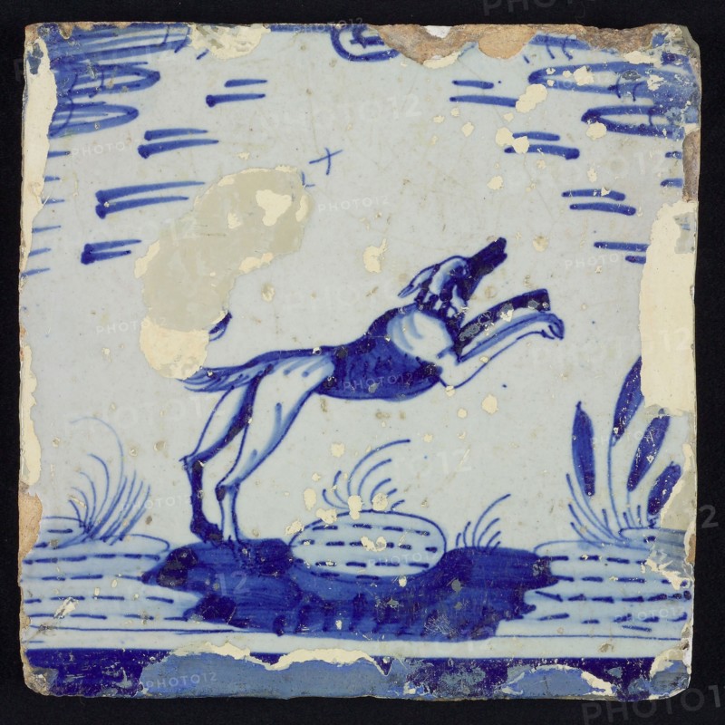 Animal tile, dog jumping over stone or soil in pond, in blue on white, wall tile tile sculpture ceramic earthenware glaze tin