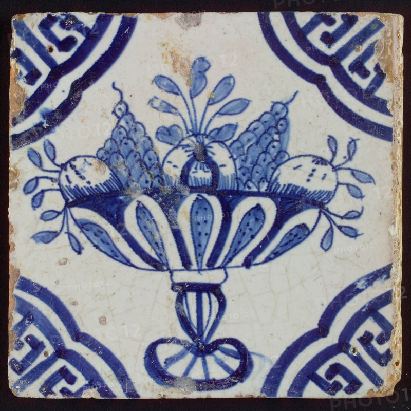 White tile with blue fruit bowl on stand, apples and grapes; corner pattern meander angle, wall tile tile sculpture ceramics