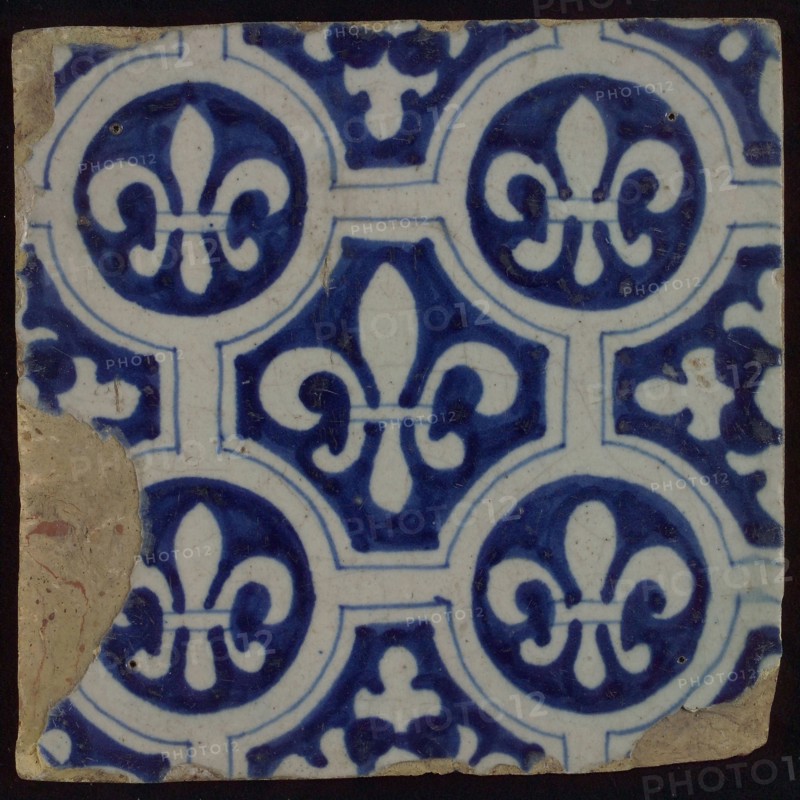 Two-tone tile, blue on white background, four circles with white French lily around central ornament with lily, wall tile