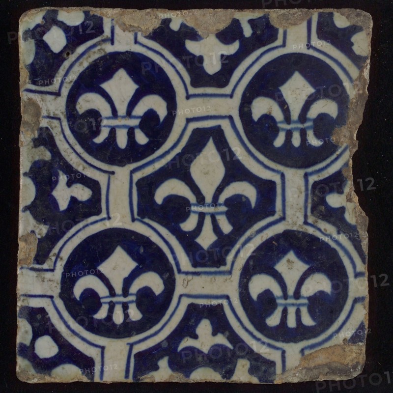 Two-tone tile, blue on white background, four circles with white French lily around central ornament with lily, wall tile
