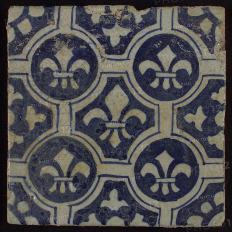 Two-tone tile, blue on white background, four circles with white French lily around central ornament with lily, wall tile