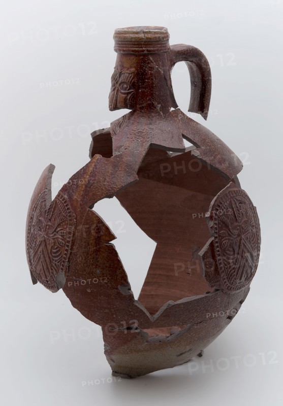 Fragments of stoneware Bartmann jug, also called Bellarmine jug, dark brown, on stand, beardmug tableware holder soil find