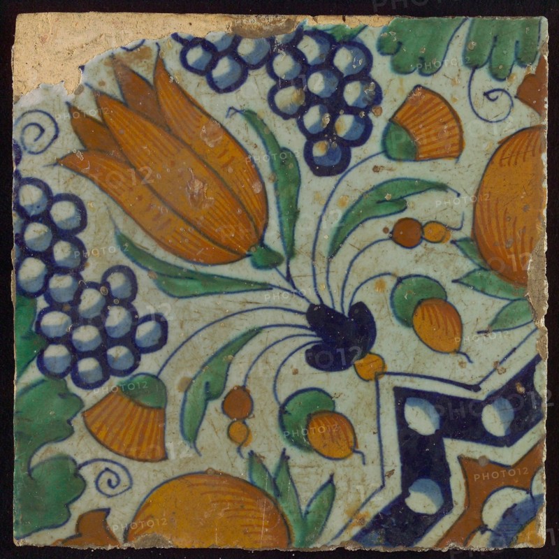 Tile, blue, green, orange and brown on white, star tulip with quarter rosette, bunches of grapes and orange-apples, wall tile