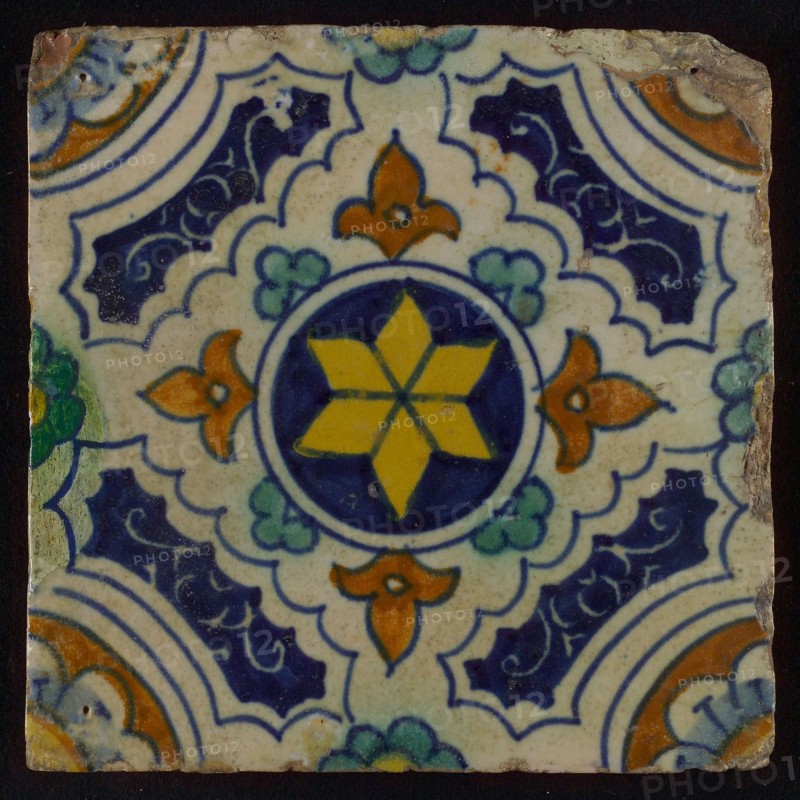 Tile, blue, green, brown and yellow on white, central yellow star in circle, sgraffito surfaces, corner motif quarter rosette