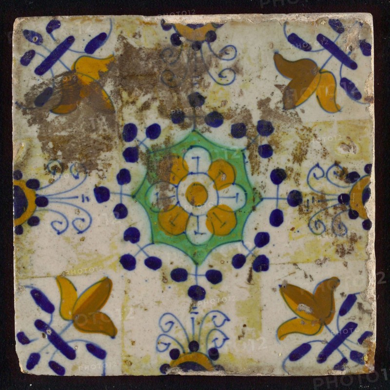 Tile, blue draft, yellow, green and orange on white, central flower within star shape, three-spot around, half rosette, corner
